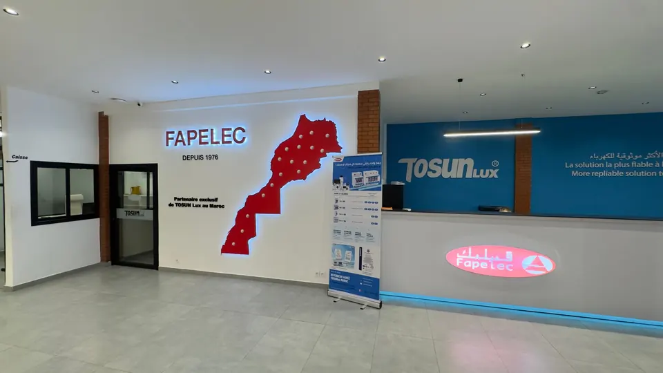 Hall d'entrée du showroom FAPELEC : enseigne lumineuse FAPELEC Depuis 1976, carte du Maroc rouge rétroéclairée et comptoir d'accueil TOSUNLUX.